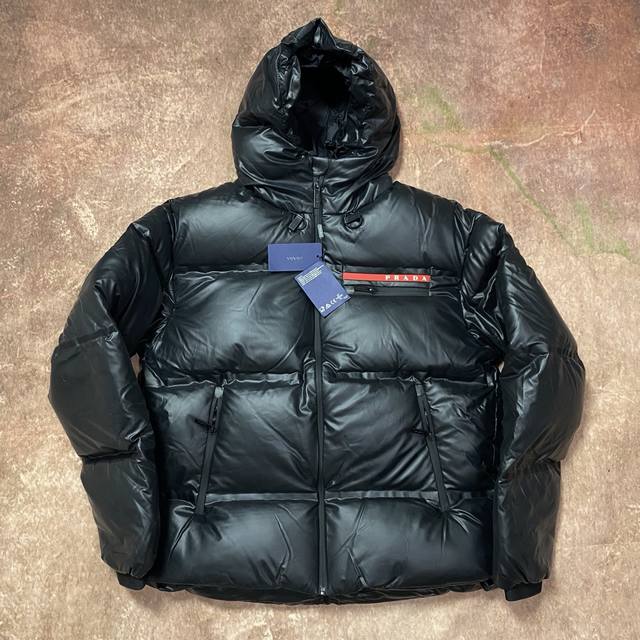 prada 普拉达经典红标羽绒服｜暗夜之光，细节定义奢华 一抹赤红，划破沉寂 唯有prada，敢以极致纯黑衬托一抹炽烈红标 不是所有羽绒服，都配得上这一道灵魂赤