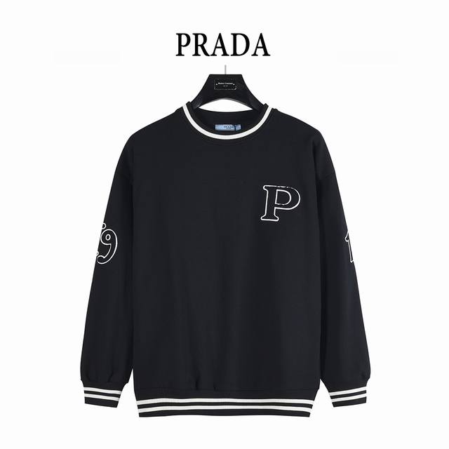 prada 普拉达 25Fw 撞色螺纹贴布字母刺绣圆领卫衣 这款运动衫呈现Oversize廓形，圆领、袖口与底边采用罗纹针织设计。 领口袖口撞色条纹点缀，增添俏