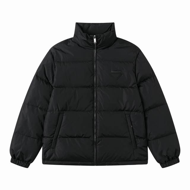 prada 25Fw新款织物三角标羽绒服 面料采用尼龙材质与传统尼龙性能相当具备高强度抗撕裂耐磨损等特性 工艺将尼龙织物材料平整的固定在冲压机台上在电脑控制下