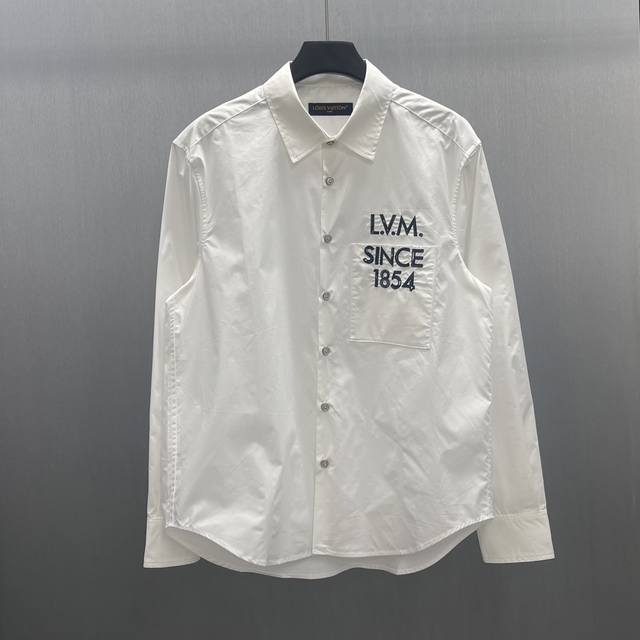 Lu 长袖标识衬衫 本款由棉质府绸剪裁的挺括村衫，因2026 年春夏秀场的 山Legacy 标识而更显精致。灵感源自路易威登个性化行李箱的历史，胸前口袋处印有模