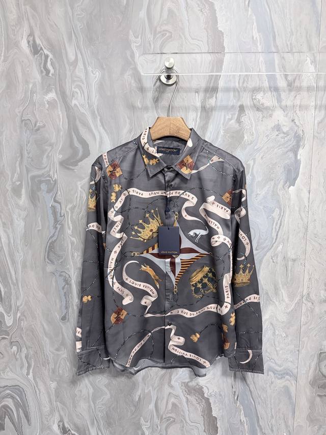 路易 25新款飘逸的衬衫采用桑蚕丝制成，饰有本系列富丽堂皇的 Lv Emblem 图案。基底印花包含饰带、品牌标识、王冠、Monogram 花卉、犬与俏皮狐狸。