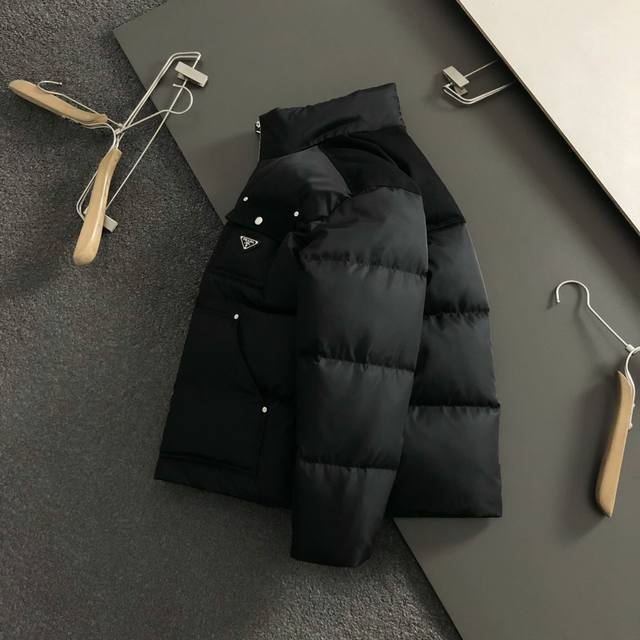 prad*合身版型48-56 2025秋冬90白鸭绒羽绒外套，以金属三角标多口袋点缀为主调，多结构融合打破传统羽绒的单调感，彰显个性与不羁。立体剪裁贴合身形，设