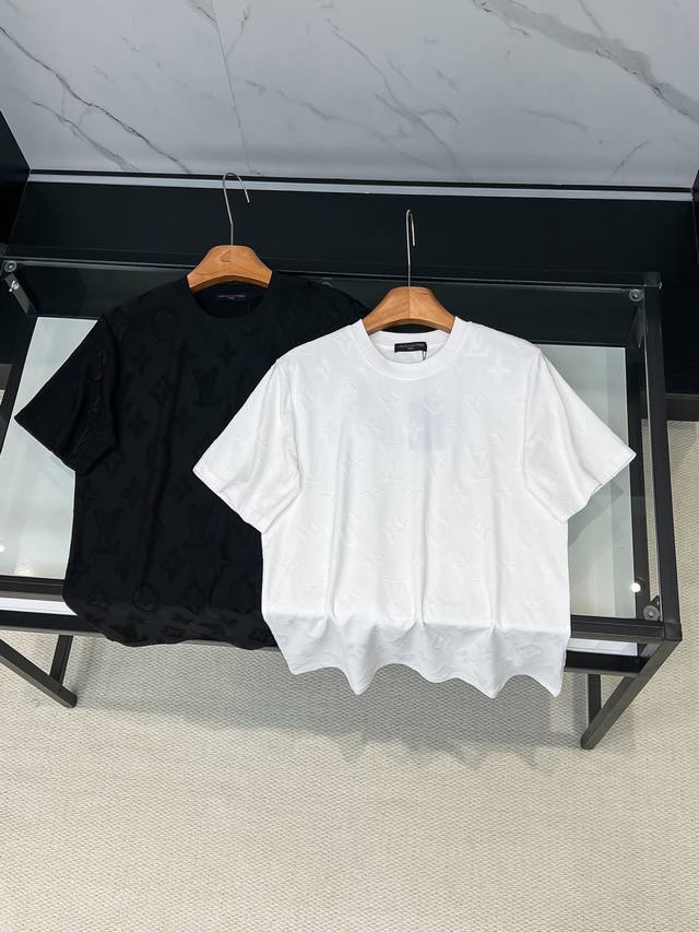 LV 26Ss新品 满印老花短袖T恤 这件白色 T 恤采用特殊的提花工艺，将经典的 Lv 老花图案立体呈现在面料表面。面料经过特殊处理，呈现出细腻的凹凸纹理，每