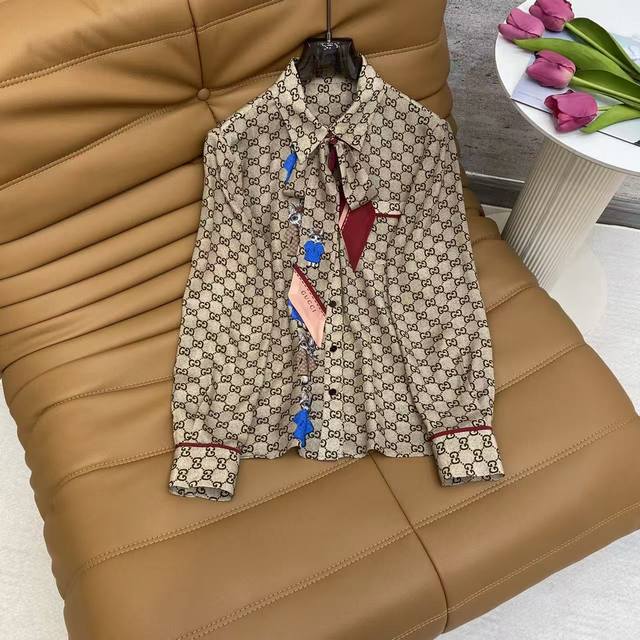 Gu2026 Sp 精品真丝衬衫 这件满印经典双G图案的衬衫，采用垂顺的丝质面料，领口搭配彩色拼布装饰与系带设计，袖口做了红色镶边细节，整体复古又充满个性，适合