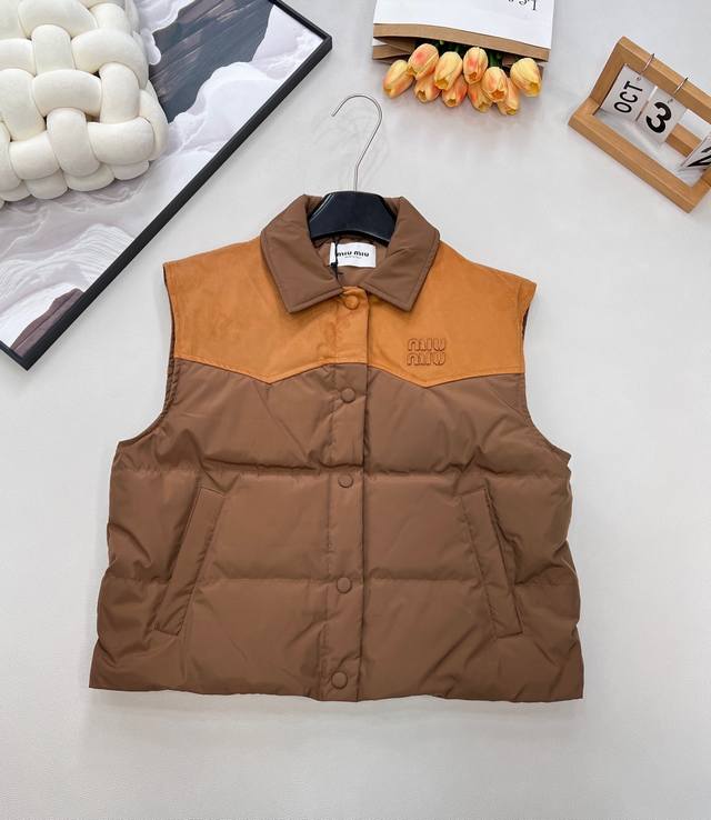 Miumiu25Fw秋冬新款皮革徽标翻领拼接撞色羽绒马甲丨独家高版出品！以皮革拼接+字母徽标为核心设计，领口 肩背区域采用焦糖棕麂皮质感皮革，与主体奶茶杏尼龙面