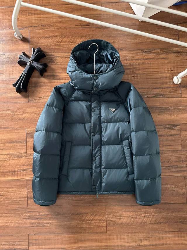 支持年后退换 Prada&普拉达Fw2025秋冬新款羽绒服。柜子在售款，一件难求。采用定制防风防雨面料，抗皱立挺有型，软糯亲肤，上身舒适度极高；胸前采用经典三角